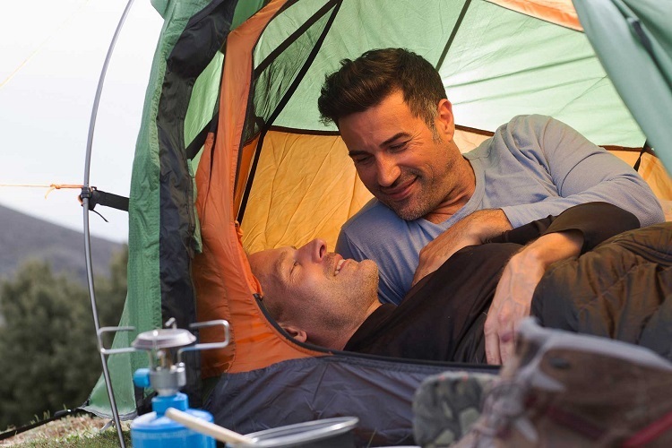 Male couple camping, resting in tent